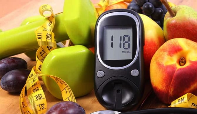 Glicosímetro mostrando uma glicemia de 118 mg/dL em meio a frutas, halteres e uma fita métrica.